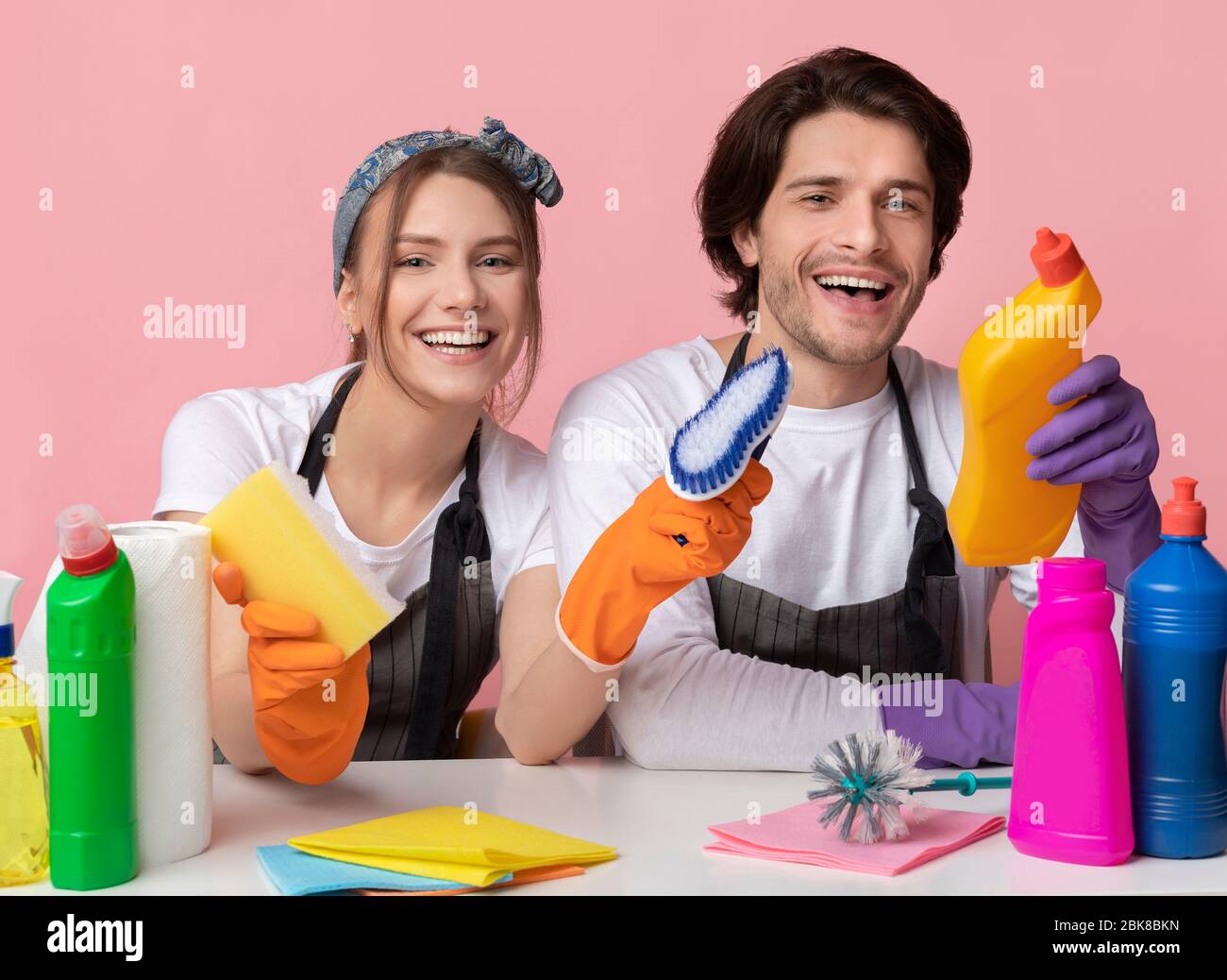 Fröhliches Paar am Tisch mit vielen Reinigungsmitteln, bereit für die Reinigung Stockfoto
