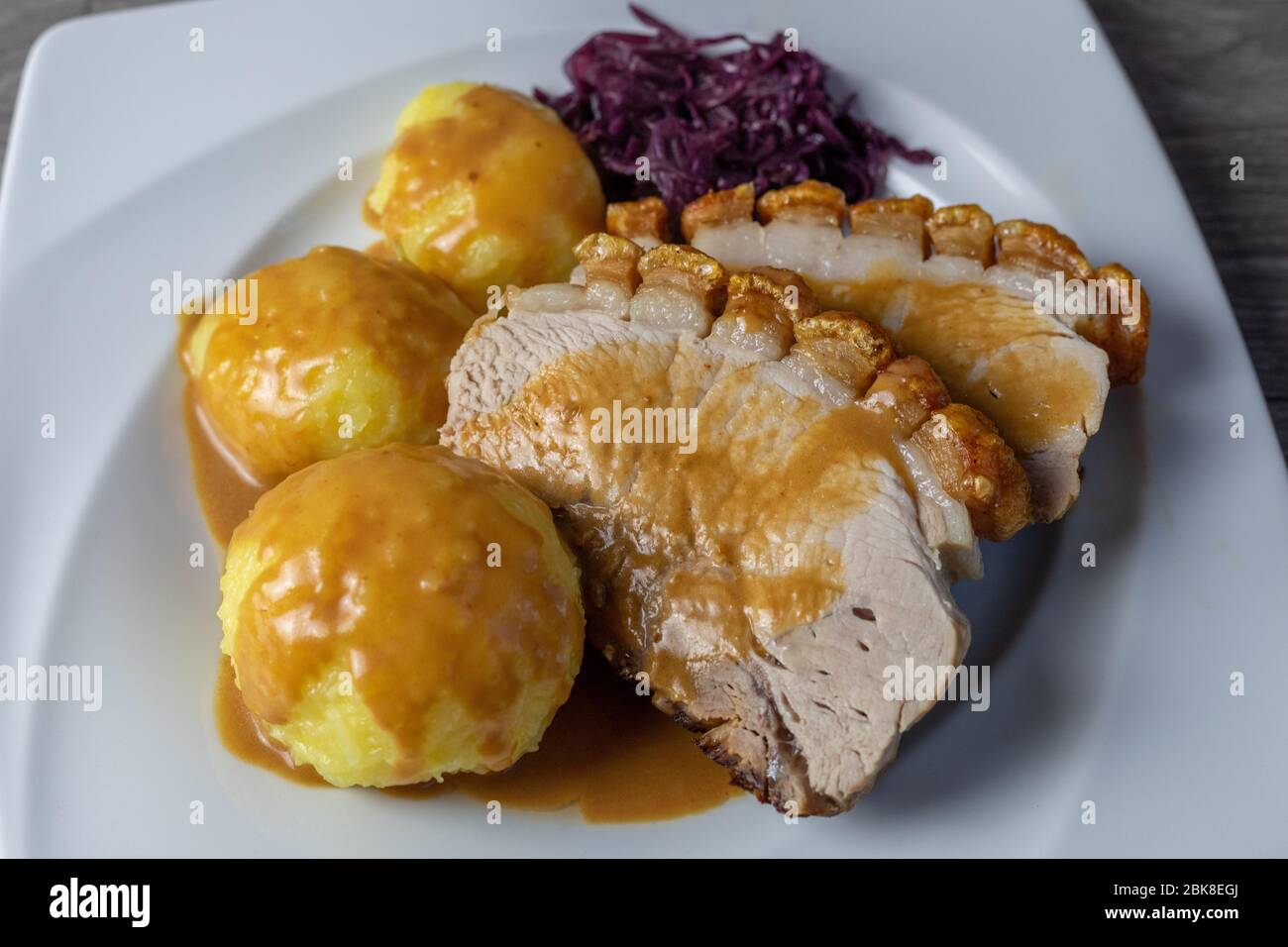 Feines Fleisch - Schweinebrot mit Krackle, Kartoffelknödel und Rotkohl Stockfoto