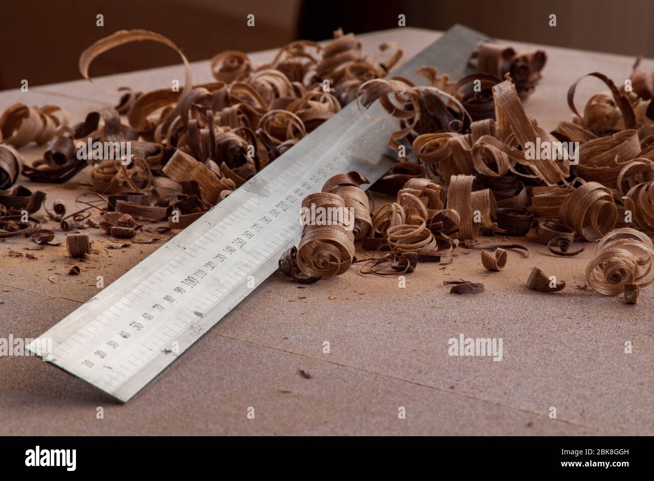 Ein gerader Stahlrand oder metrisches Lineal bleibt in Holzspänen auf der staubigen Werkbank Stockfoto