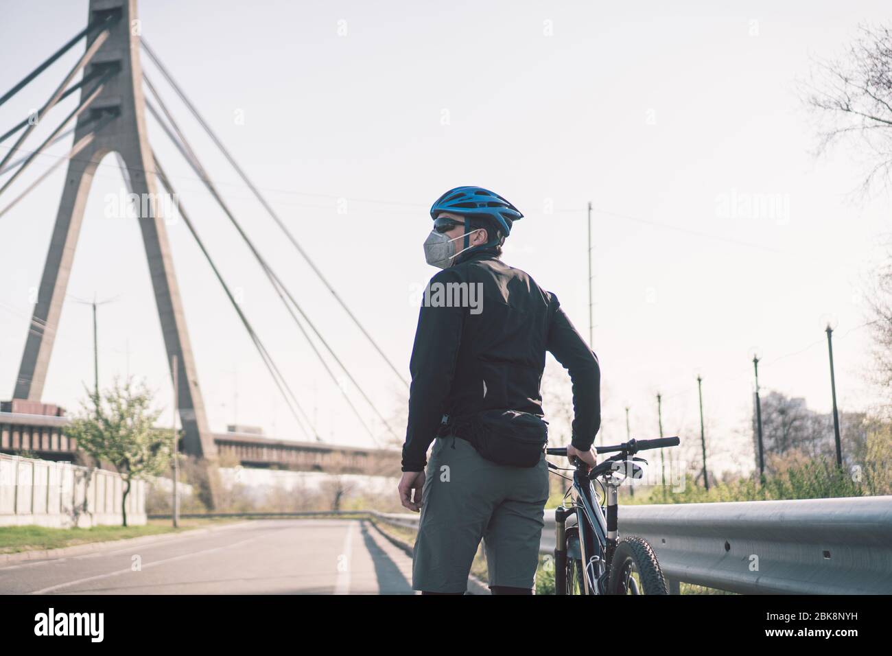 Radfahrer in Smog getönt Stadt in N95 Maske. Luftverschmutzung. Industriestadt. Mann in Maske aus Staub. Typ in Atemschutzmaske mit Filter pm 2.5. Thema Covid Stockfoto