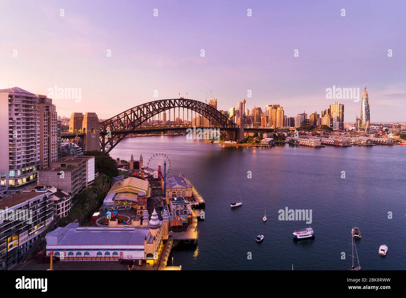 Blick aus der Luft auf den Unterhaltungspark und den Gehweg am Ufer der Lavender Bay im Hafen von Sydney bei Sonnenaufgang. Stockfoto