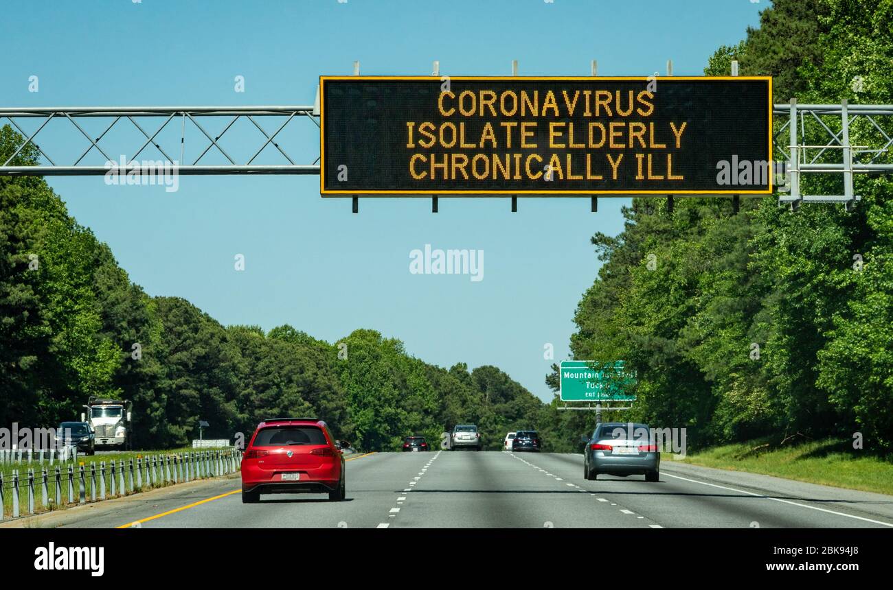 Coronavirus Pandemie Gesundheitswarnung über dem Verkehrsschild auf dem Highway 78 in Atlanta, Georgia, fordert Isolierung von älteren und chronisch kranken Menschen. (USA) Stockfoto