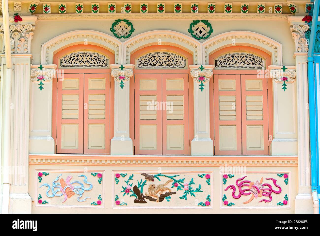 Traditionelles chinesisches Straits-Ladenhaus mit antiken Pfirsich- und weißen Holzfensterläden und prunkvollem farbenfrohem Äußeren im historischen Joo Chiat, Singapur Stockfoto