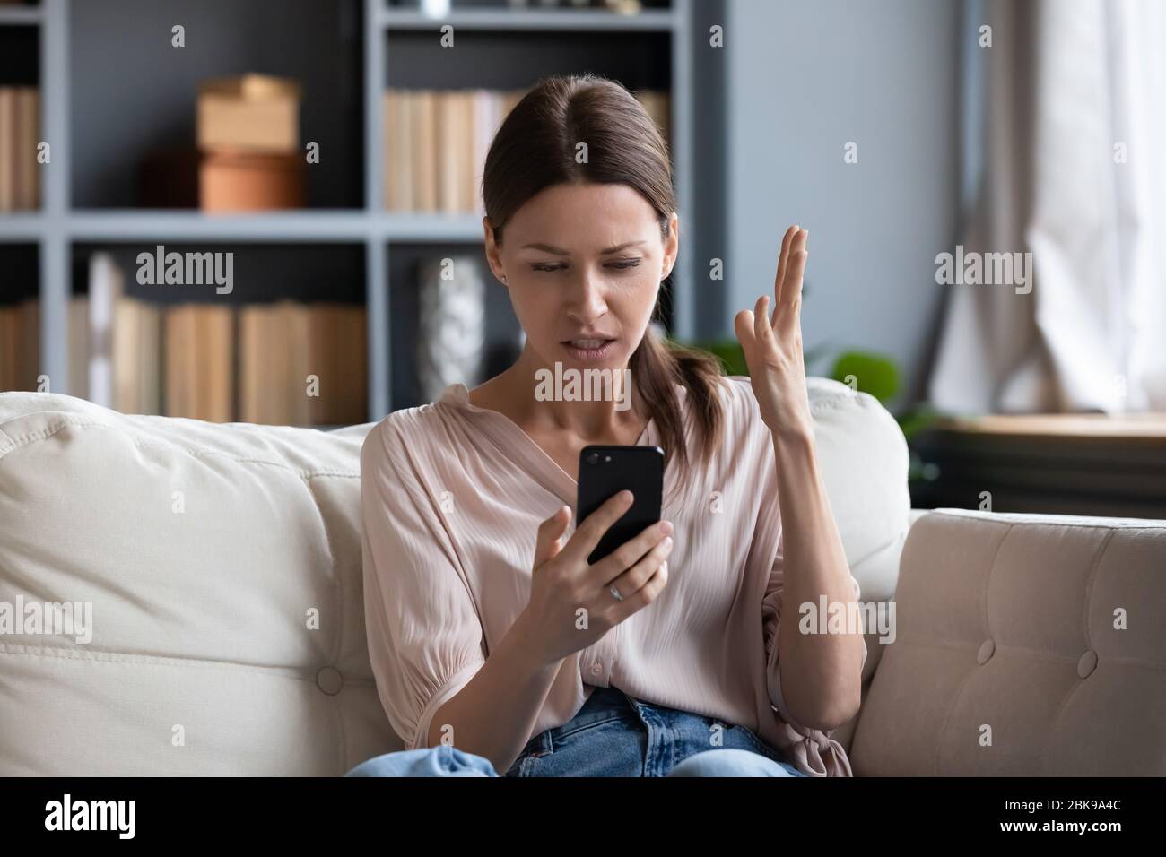 Verwirrt wütend junge Frau, die Probleme mit dem Telefon Stockfoto