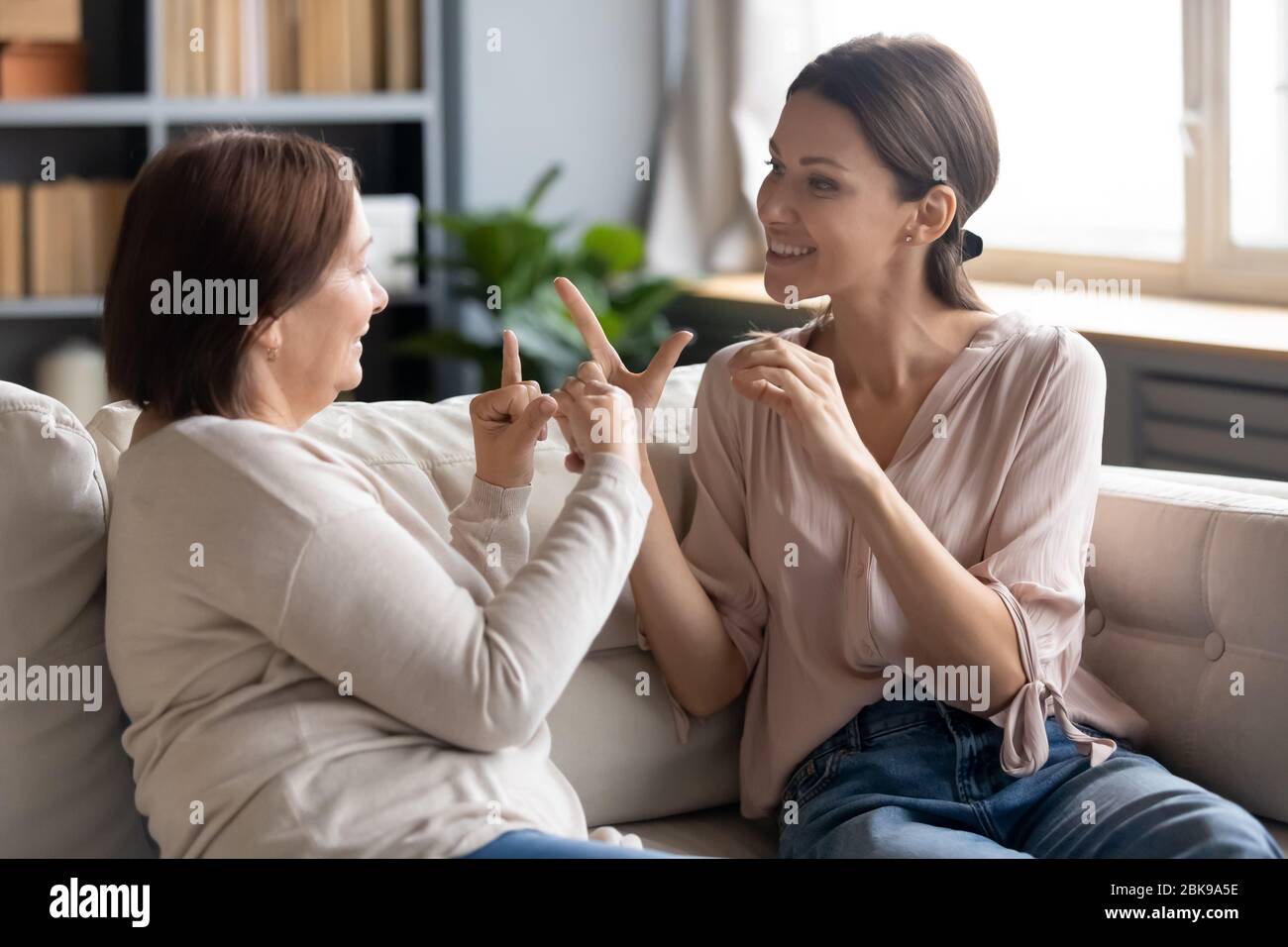 Glückliche Erwachsene Tochter und ältere Mutter spricht Gebärdensprache Stockfoto