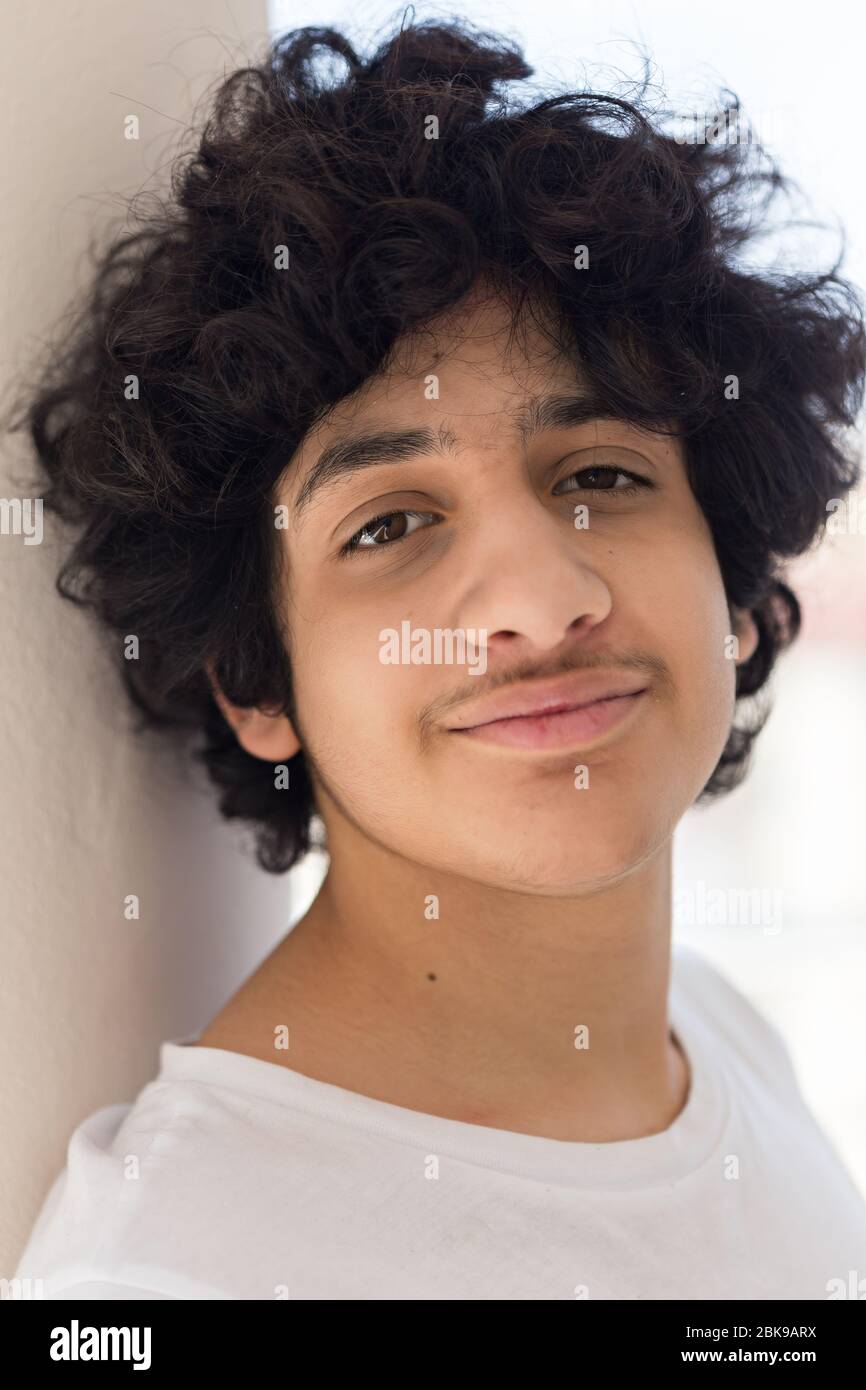 Vertikaler Kopf und Schultern Portarit eines Teenagers Jungen mit schwarzen, unordentlichen Haaren, mit weißem T-Shirt. Stockfoto