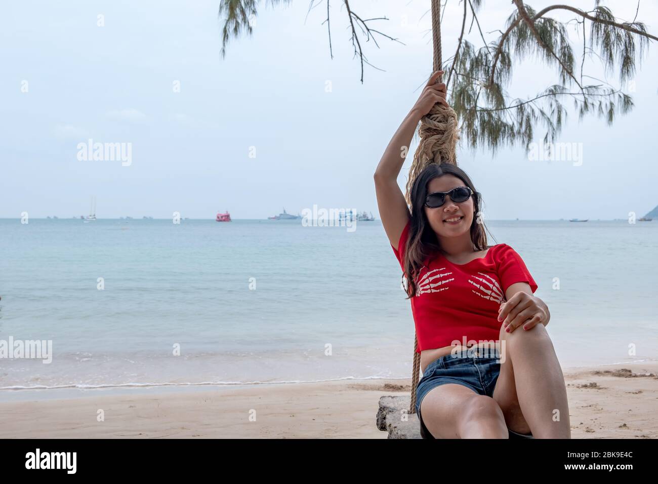 Lächelnde thai-Dame auf einer Schaukel am tropischen Strand an sonnigen Tag. Thai Mädchen genießen am Strand. Stockfoto