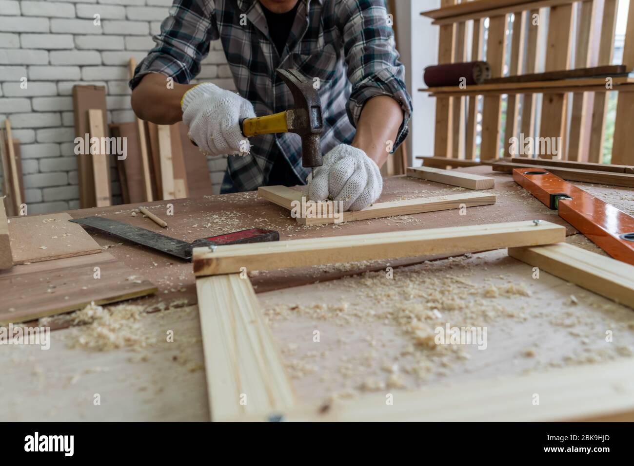 Tischler, der in der Werkstatt für Holzhandwerk arbeitet, um Baumaterial oder Holzmöbel herzustellen. Der junge asiatische Zimmermann verwendet professionelle Werkzeuge für Stockfoto