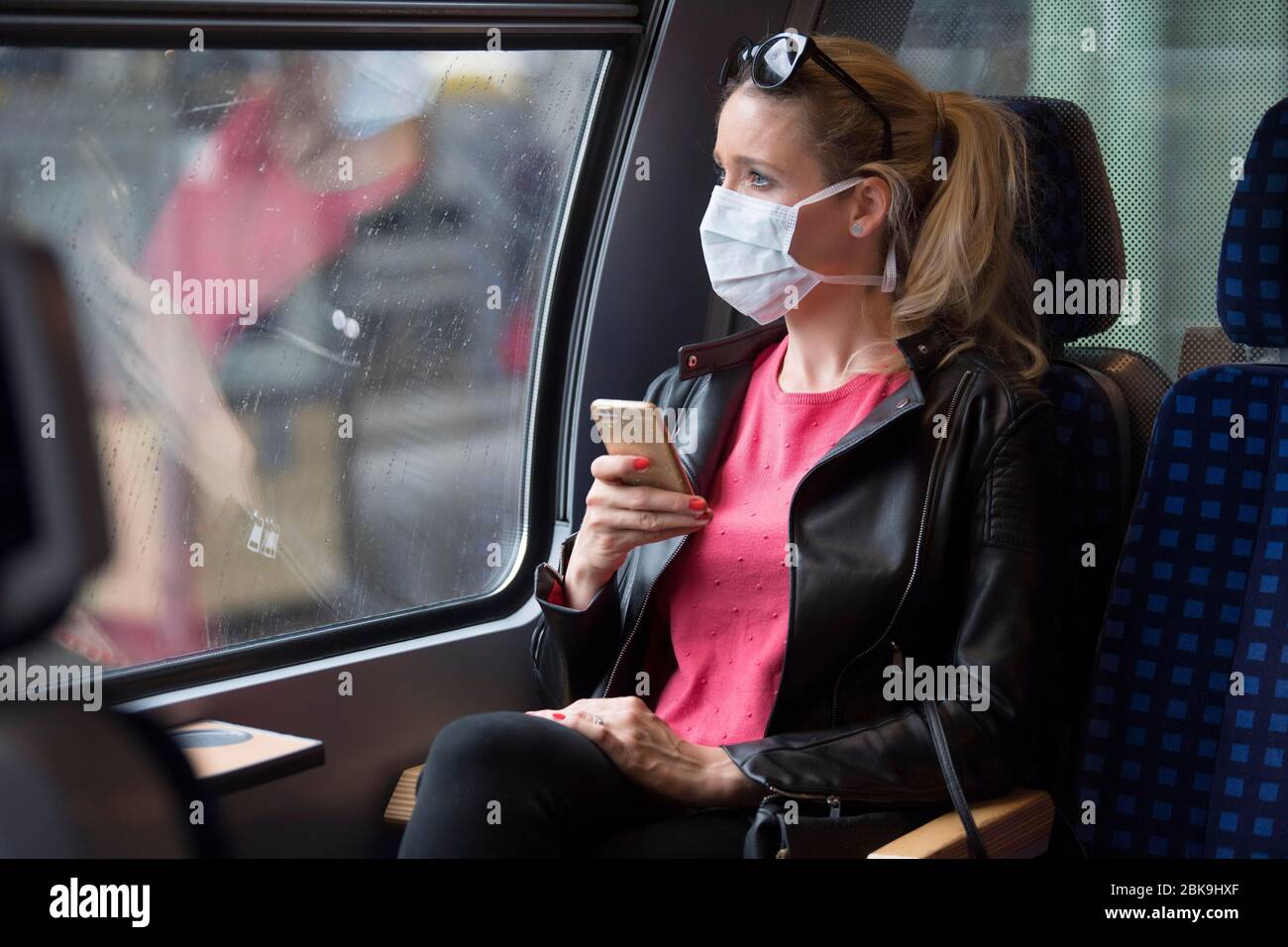 Frau mit Gesichtsmaske, in Zug sitzend, auf ihrem Handy, Corona-Krise, Stuttgart, Baden-Württemberg, Deutschland Stockfoto