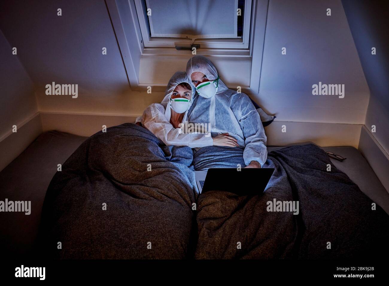 Paar in Schutzkleidung im Bett Filme ansehen, Sylt, Deutschland Stockfoto