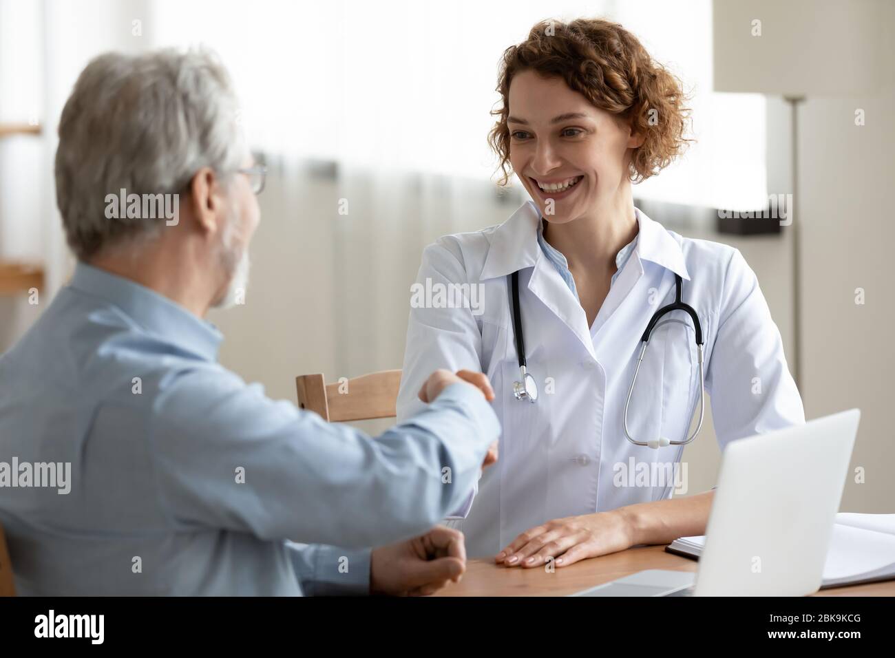 Lächelnde Ärztin Händeschütteln Gruß gesund Senior männlichen Patienten Stockfoto