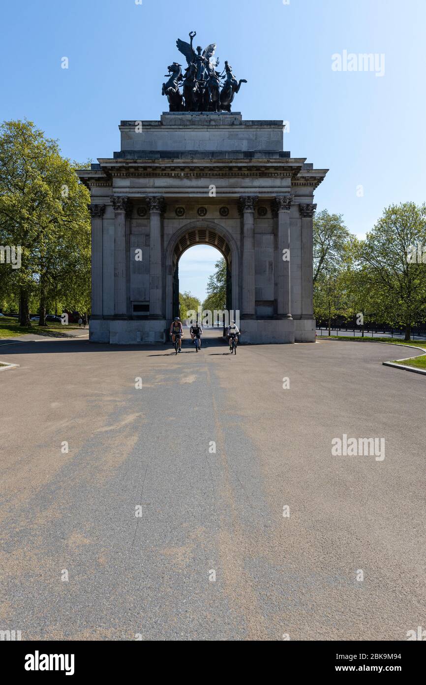 Lockdown London: Drei Radfahrer radeln durch den Wellington Arch am Hyde Park Corner, der einst die kleinste Polizeistation Londons enthielt. Stockfoto