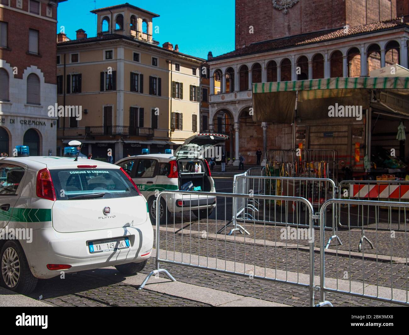 Cremona, Lombardei, Italien - 2. Mai 2020 - Polizeibeamter, der die Körpertemperatur kontrolliert und den Zugang zum Open-Air-Lebensmittelmarkt im Stadtzentrum kontrolliert Stockfoto