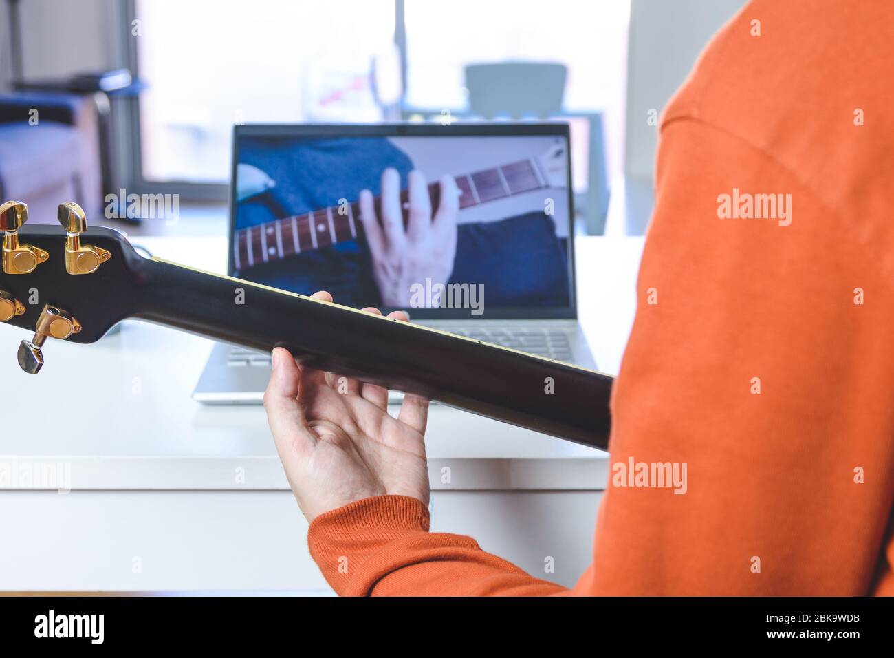 kaukasischer Mann lernen Gitarre mit einem laptopkaukasischen Mann lernen, akustische Gitarre mit Video-Unterricht Stockfoto