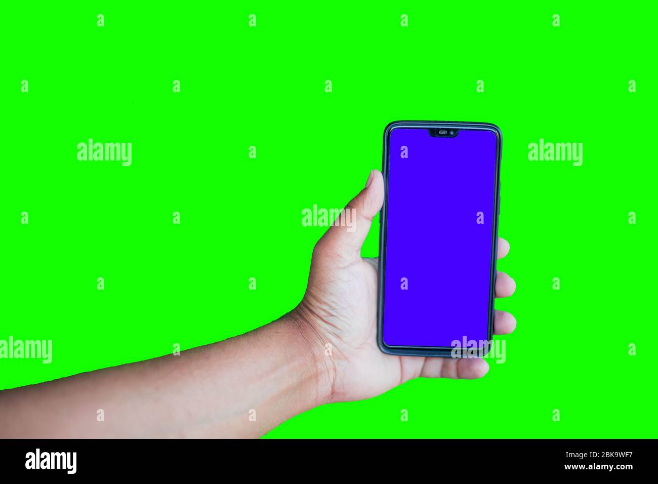 Mann hält Telefon mit Chroma-Taste-Display vor dem grünen Bildschirm Hintergrund Stockfoto