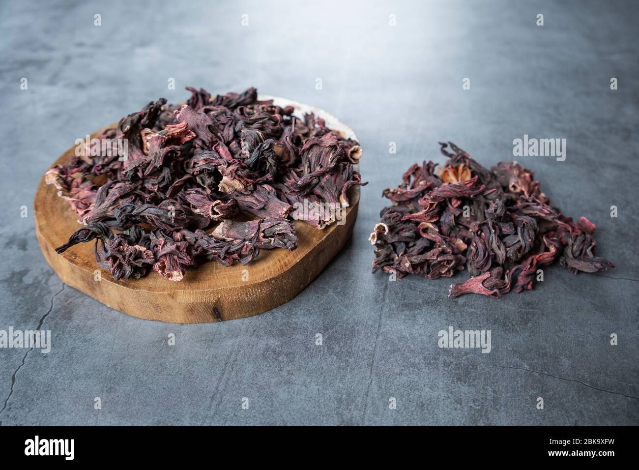 Hibiscus Tee in Holz Servierbrett auf Stein, Beton Hintergrund. Trockene, biologische, gesunde und entspannende Kräuter. Stockfoto