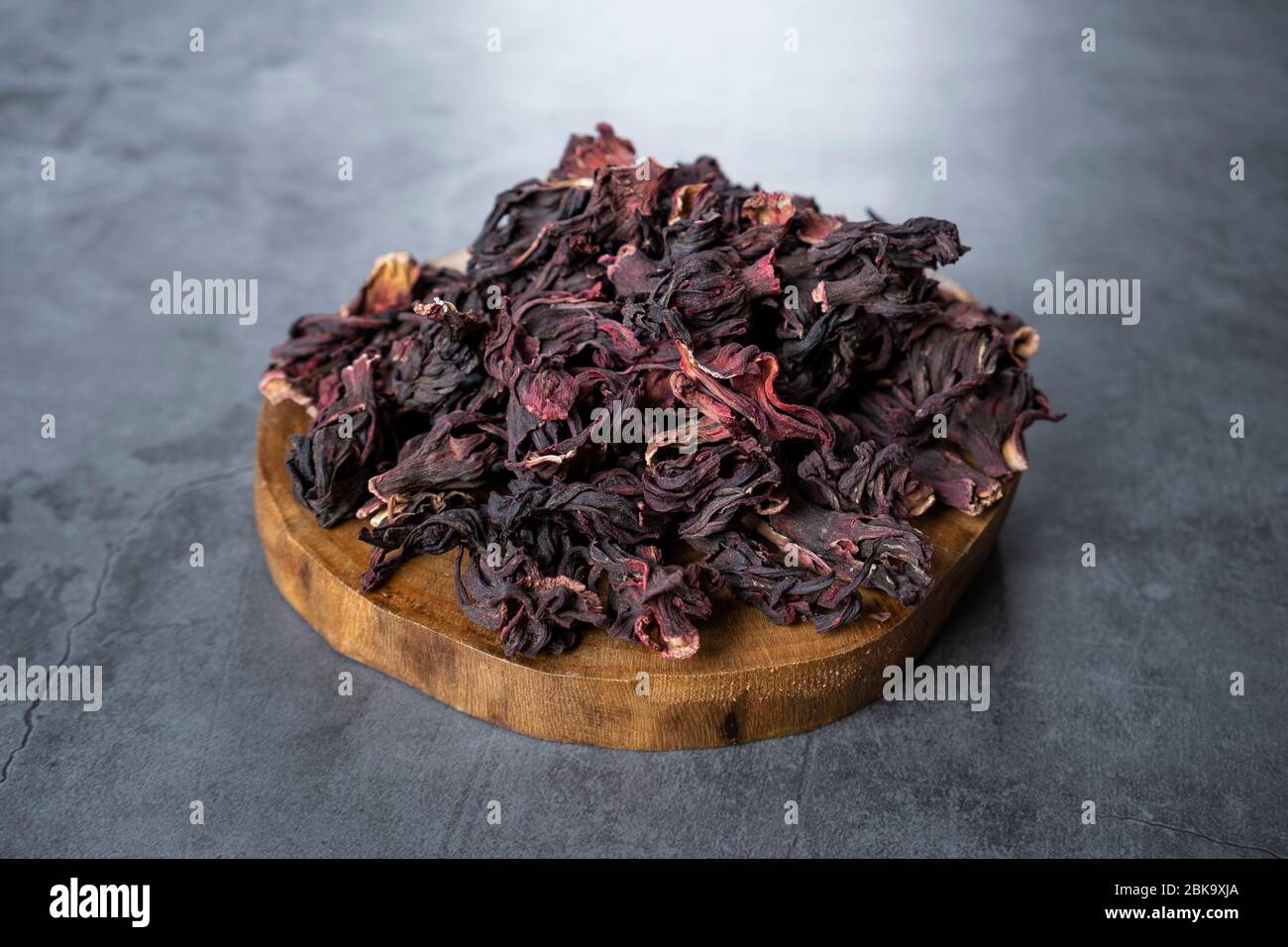 Hibiscus Tee in Holz Servierbrett auf Stein, Beton Hintergrund. Trockene, biologische, gesunde und entspannende Kräuter. Stockfoto