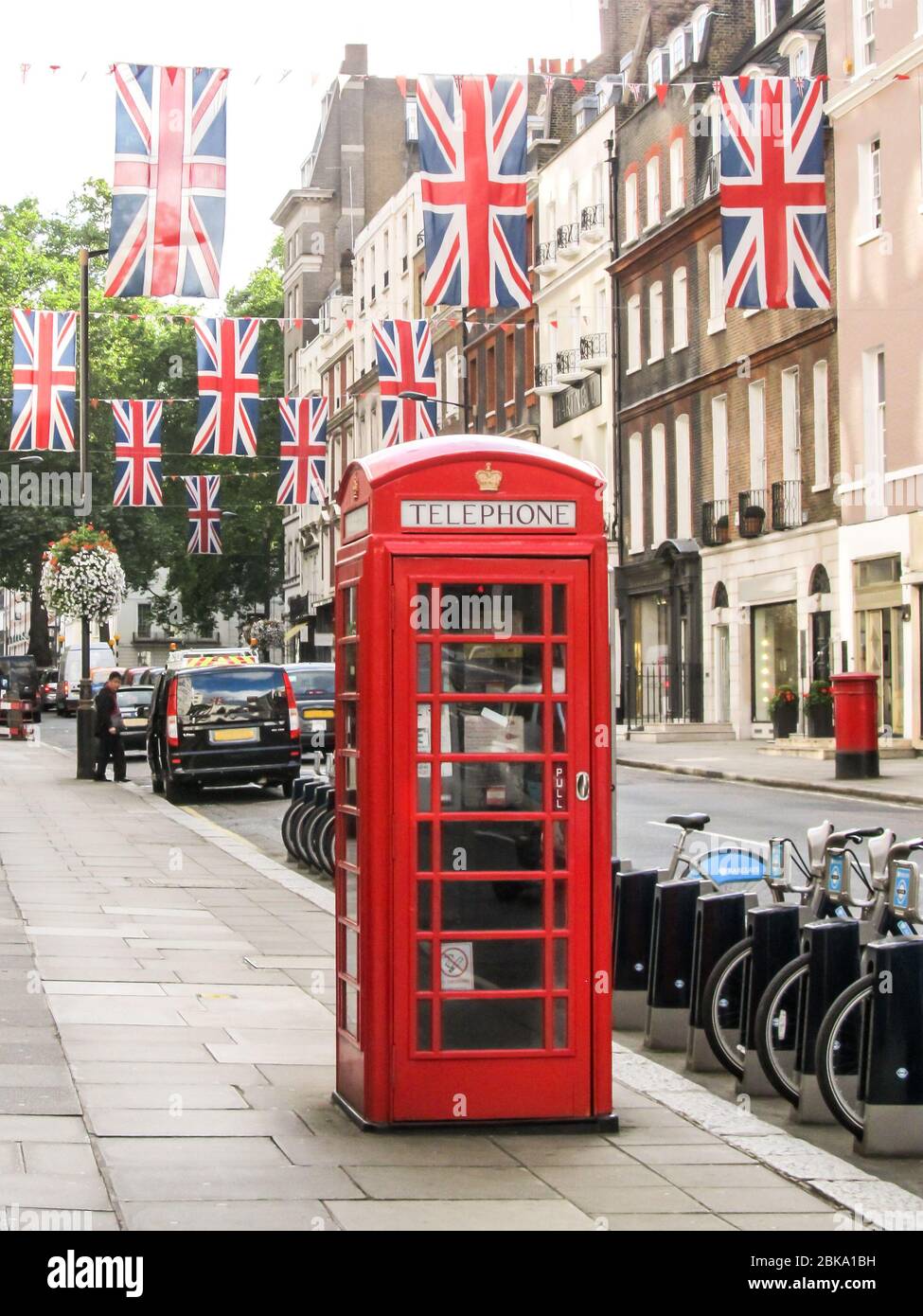 Eine der ikonischen roten britischen Telefonzellen, in einer typischen Londoner Straße, die mit Strings von UK Flags dekoriert ist Stockfoto