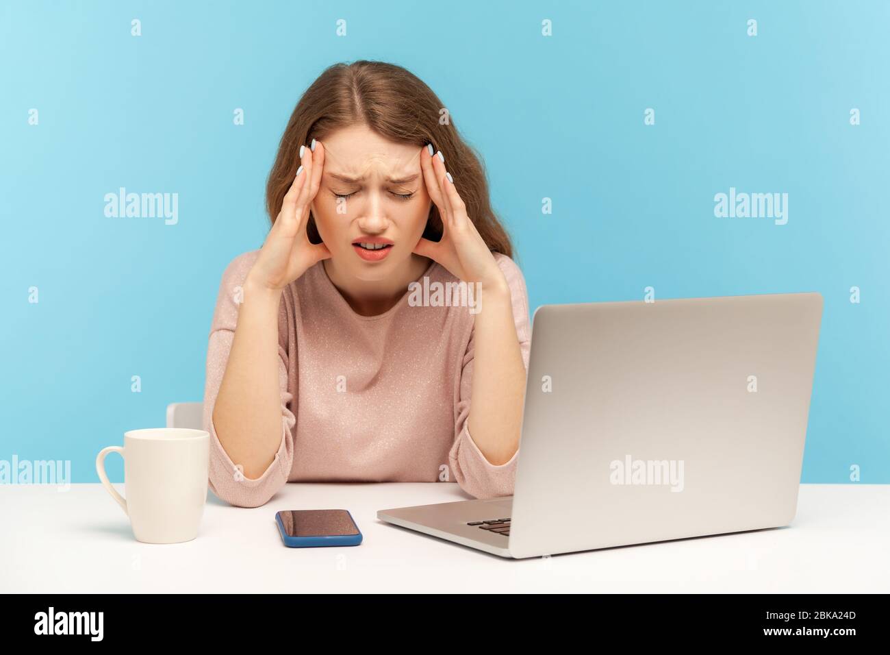 Frustrierte müde junge Frau Mitarbeiterin sitzt am Arbeitsplatz mit Laptop und schmerzhaften Kopf, leiden intensive Migräne, Überarbeit und stressigen jo Stockfoto