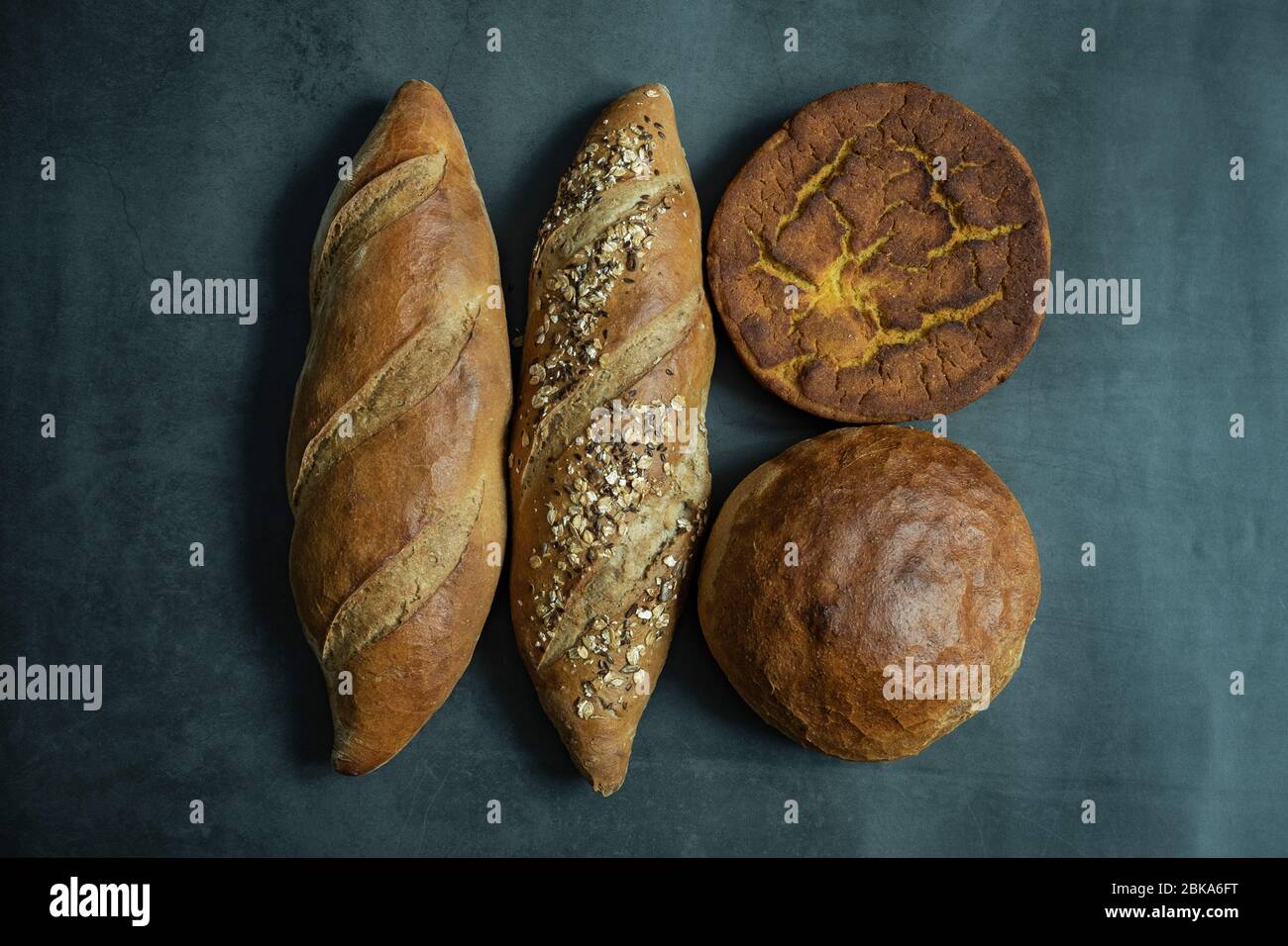 Frisch gebackenes Brot, Hafer, Mais und braunes Brot auf Betongrund. Gesunde, köstliche und hausgemachte Speisen. Flach liegend, Draufsicht. Stockfoto