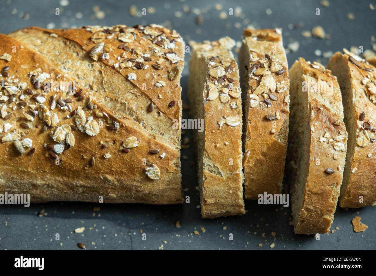 Frisch gebackenes und in Scheiben geschnittenes Haferbrot mit Krümel auf Betongrund. Gesunde, köstliche und hausgemachte Speisen. Nahaufnahme, Nahaufnahme. Stockfoto
