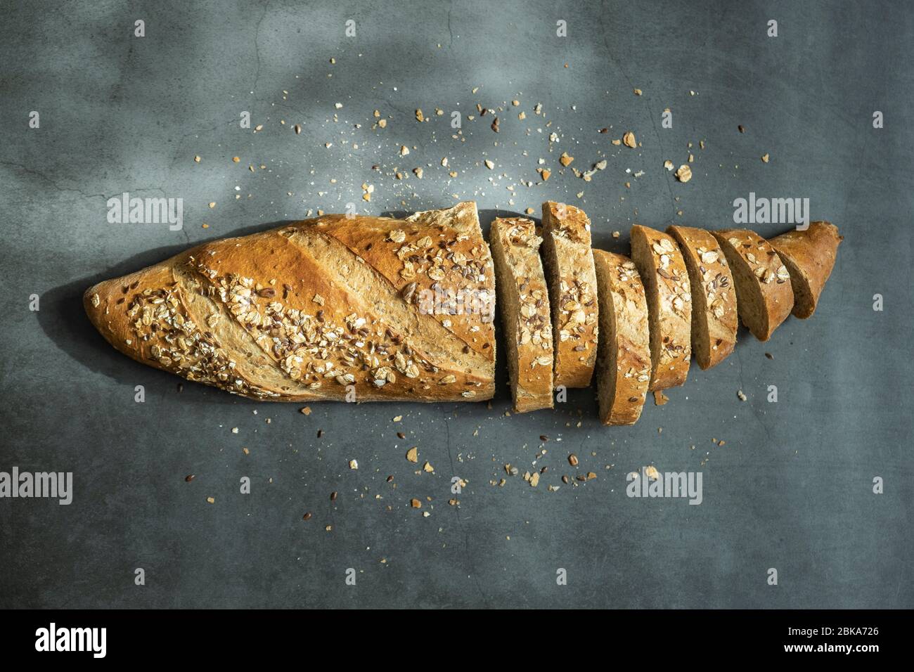 Frisch gebackenes und in Scheiben geschnittenes Haferbrot mit Krümel auf Betongrund. Gesunde, köstliche und hausgemachte Speisen. Draufsicht, flaches Lay. Stockfoto