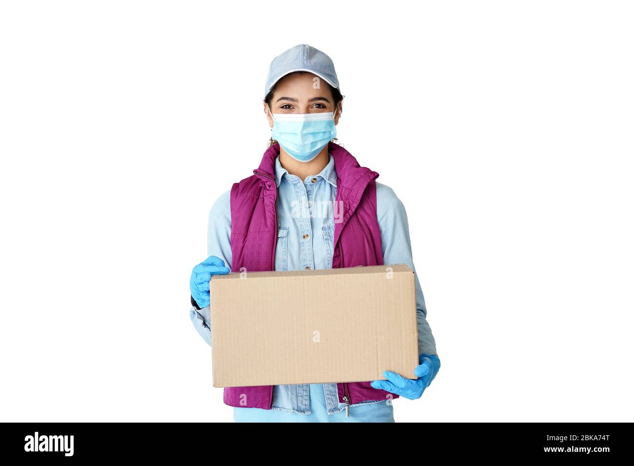 Hispanic Frau Kurier trägt Maske Handschuhe halten Lieferbox isoliert auf weiß. Stockfoto