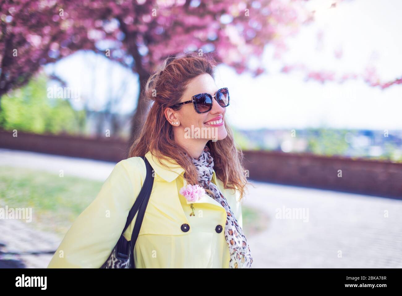 Fröhliche junge positive Frau genießt Sakura im Frühling, toothy Lächeln Stockfoto