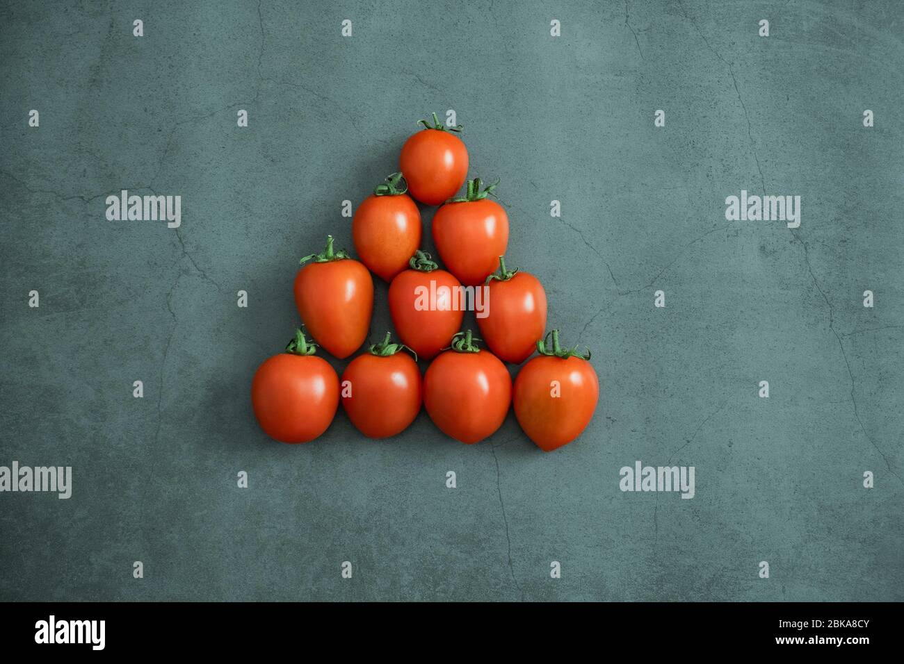 Rote kleine Kirschtomaten auf Stein, Betongrund. Frisch geerntetes leckeres, gesundes und biologisches Gemüse. Flach liegend, Draufsicht. Stockfoto