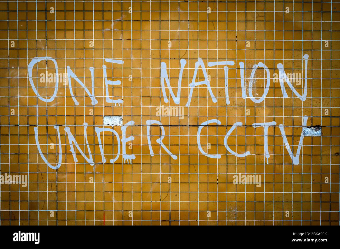 Grungy Graffiti an einer Mauer in Großbritannien Saying One Nation under CCTV Stockfoto