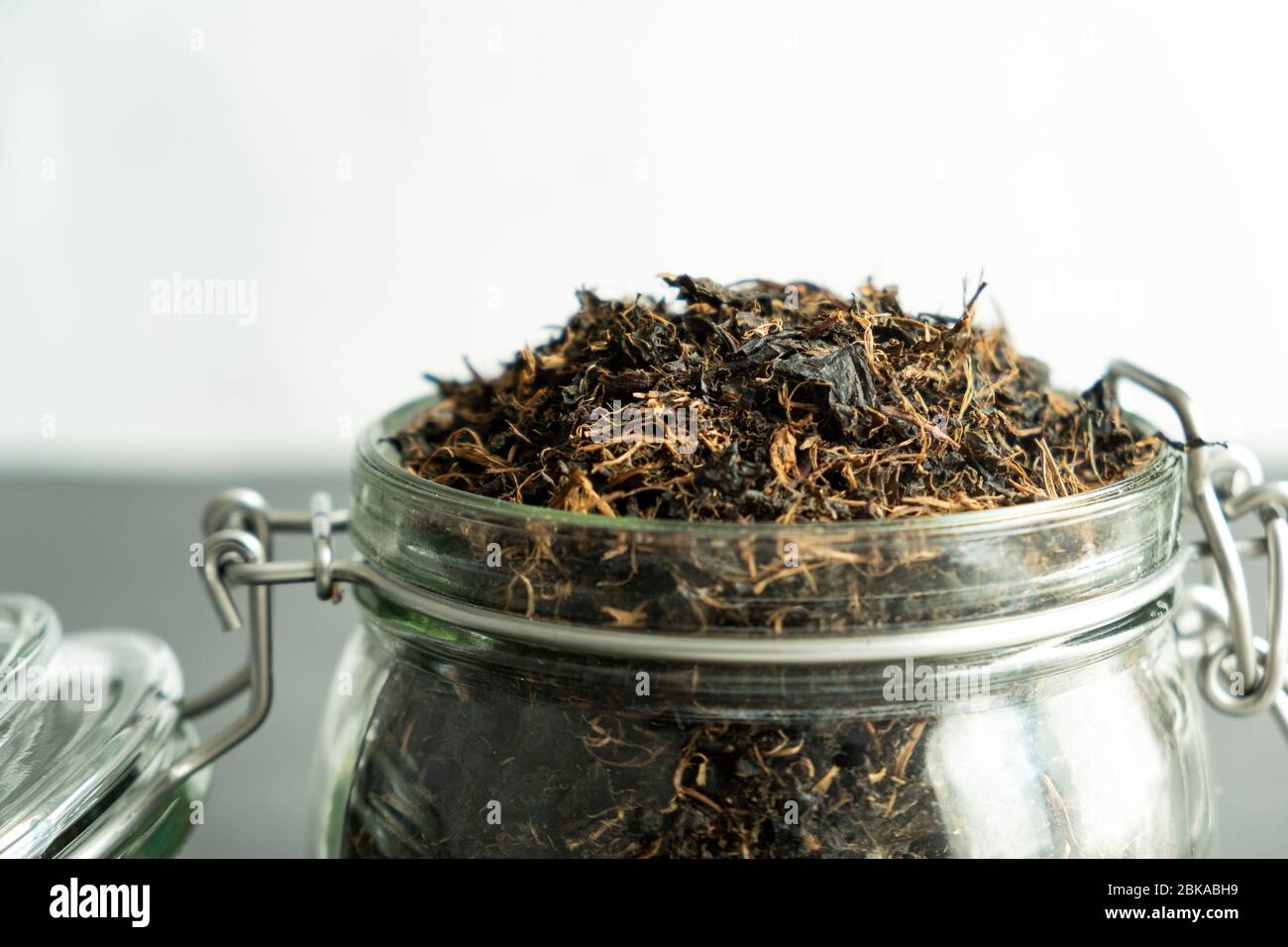 Trockenes schwarzes Teeblatt im Glasgefäß. Traditionelles, gesundes und biologisches Getränk. Stockfoto
