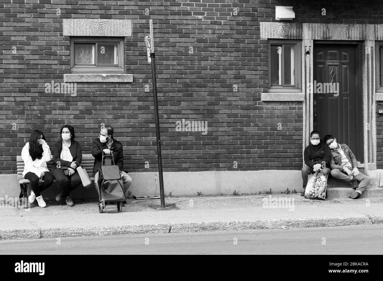 Menschen warten auf den Bus während der Covid 19 Pandemie , in Park Extension , einem Einwanderungsviertel von Montreal Kanada Stockfoto