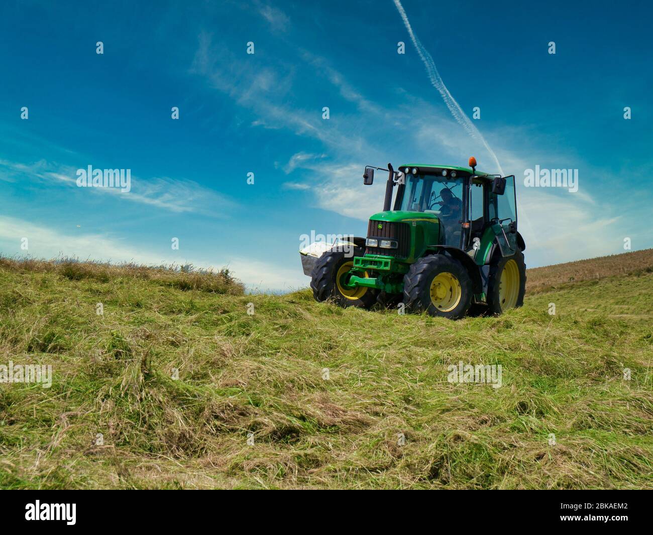 Ein Landtraktor, der Silageflder auf der Halbinsel Llyn, Gwynedd, Wales, Großbritannien durchführt Stockfoto