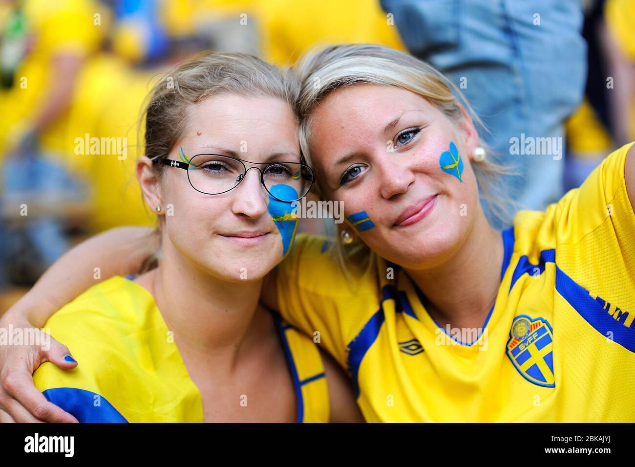 Zwei schwedische Fußballfans, Gesichter in gelb-blauen Nationalfarben gemalt unterstützen ihre Fußballmannschaft auf der Straße Stockfoto