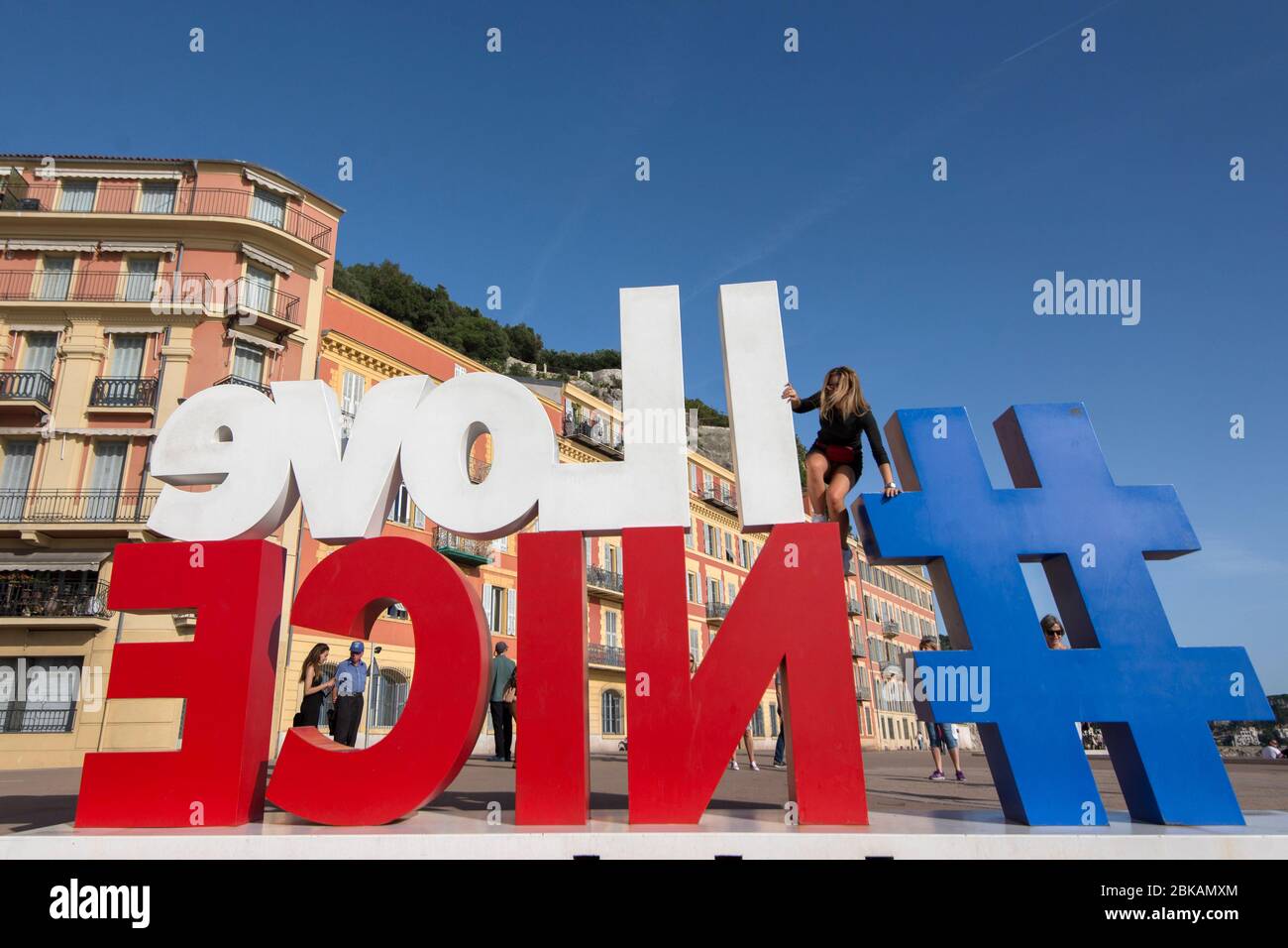 Mädchen klettert auf der Rückseite des I Love Nice Schilds Stockfoto