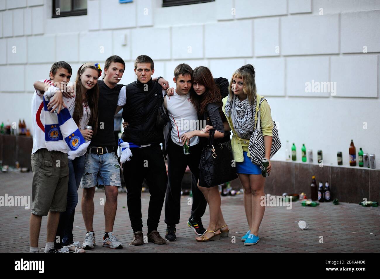 Gruppe von betrunkenen Teenagern, Jungen und Mädchen, Bier trinken und rauchen auf der Straße, viele leere Bierflaschen auf einem Hintergrund Stockfoto