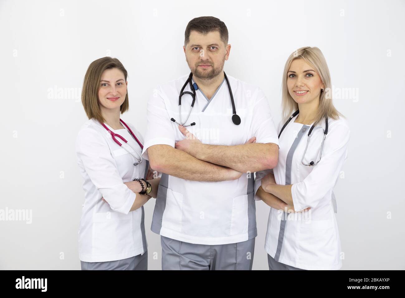 Junges Ärzteteam mit Stethoskopen in moderner Uniform, ein Porträt an einer weißen Wand. Stockfoto