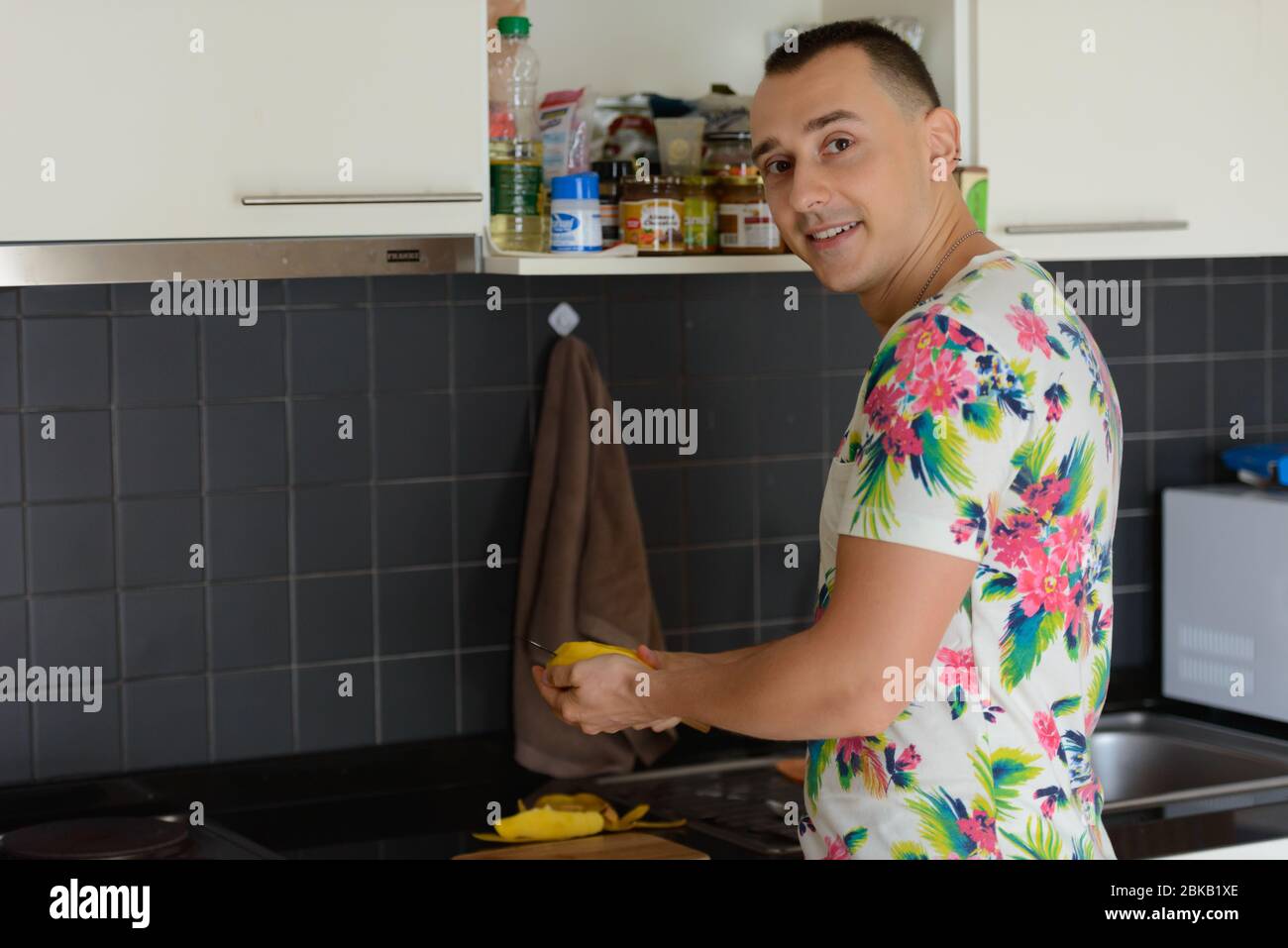 Glücklich gut aussehender Mann, der Essen in der Küche zu Hause zubereitet Stockfoto