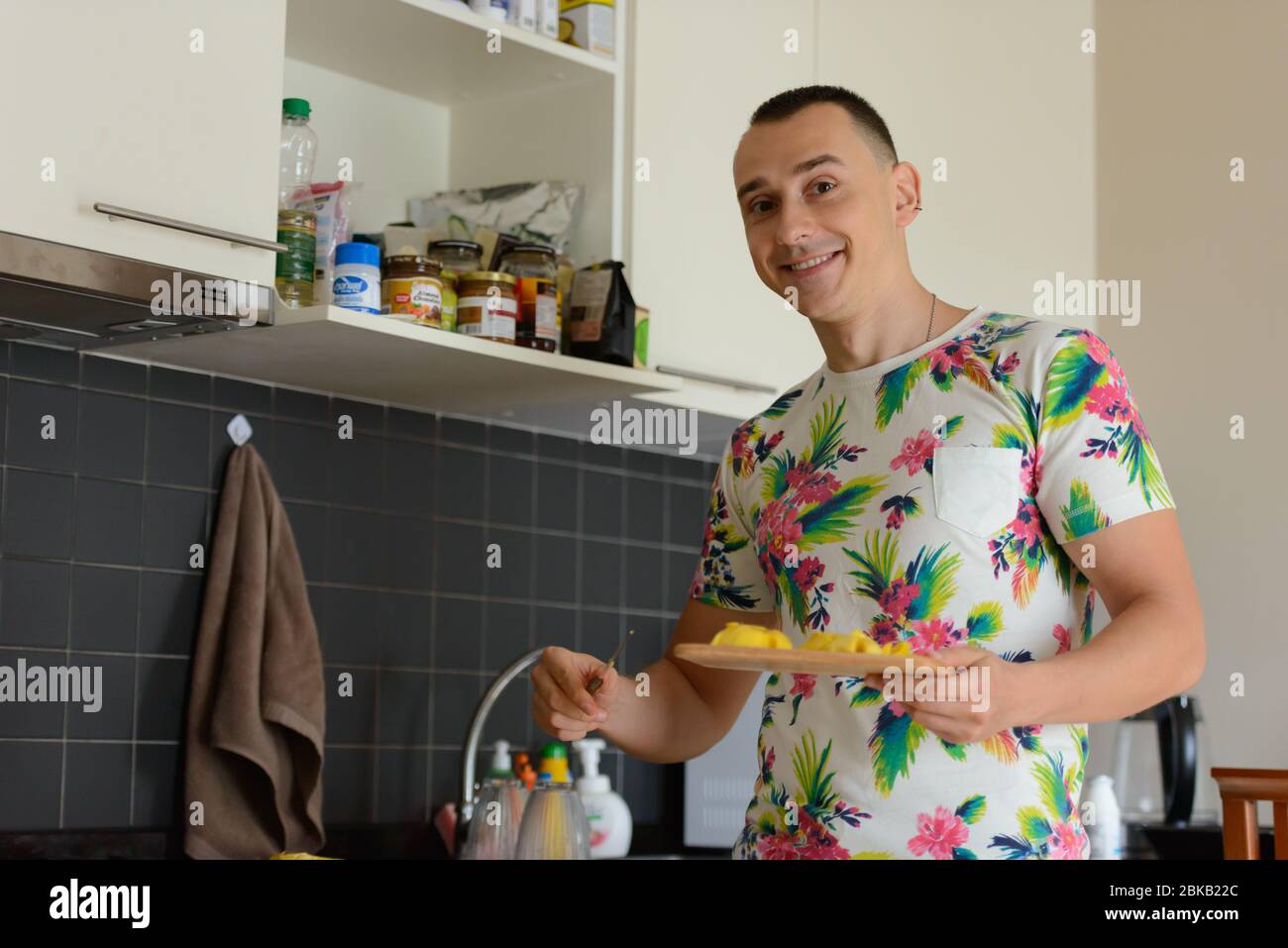 Glücklich gut aussehender Mann, der Essen in der Küche zu Hause zubereitet Stockfoto