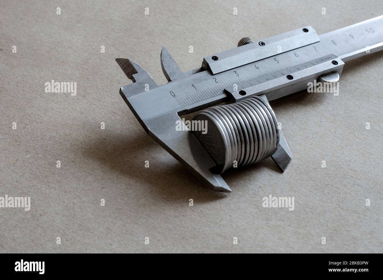Ein Close-up-Caliper misst die Anzahl der Münzen. Ukrainische Münzen mit einem Nominalwert von 5 Kopeken. Die Größe von Korruption, Bestechung. Ansicht von oben in einem Winkel Stockfoto