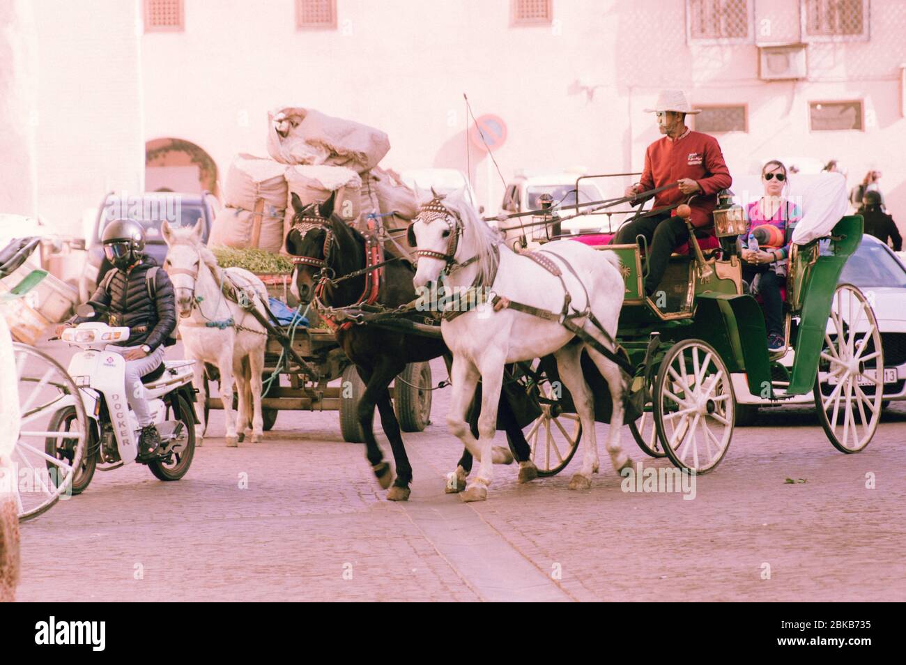 Pferdewagen Kutschen vor El Badii Palace in Marrakesch (Marrakesch) auf den Straßen der Aushandlung Motorroller und anderen Datenverkehr Stockfoto