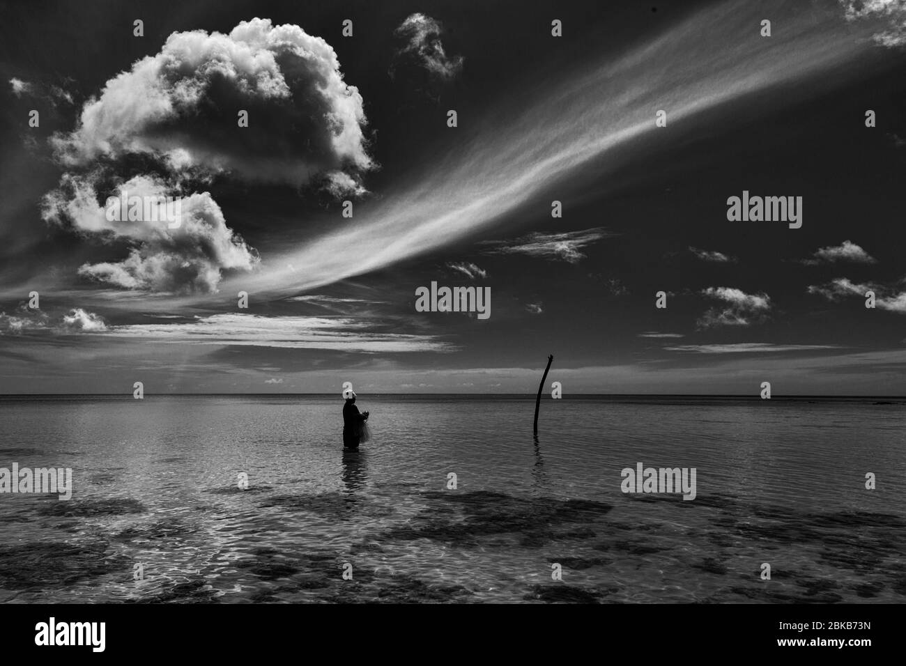 Traditionelle Fischerei in flachen Wasser unter Wolken schwarz und weiß Stockfoto