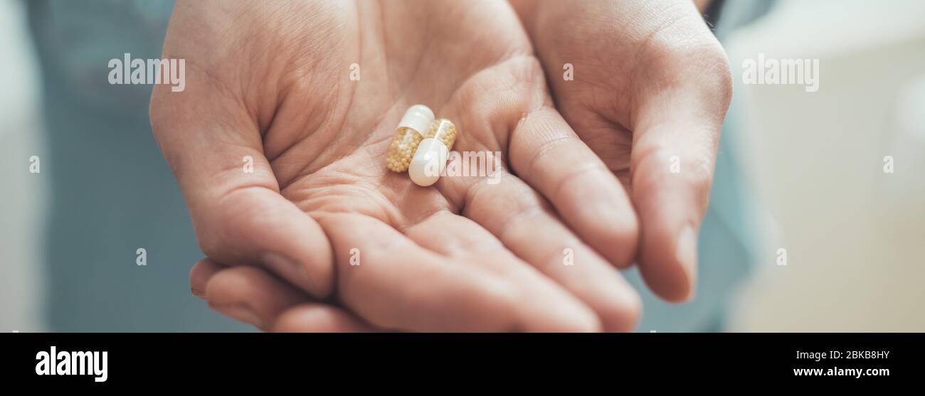 Männliche Hand hält Medikament oder Vitaminpille in Stockfoto