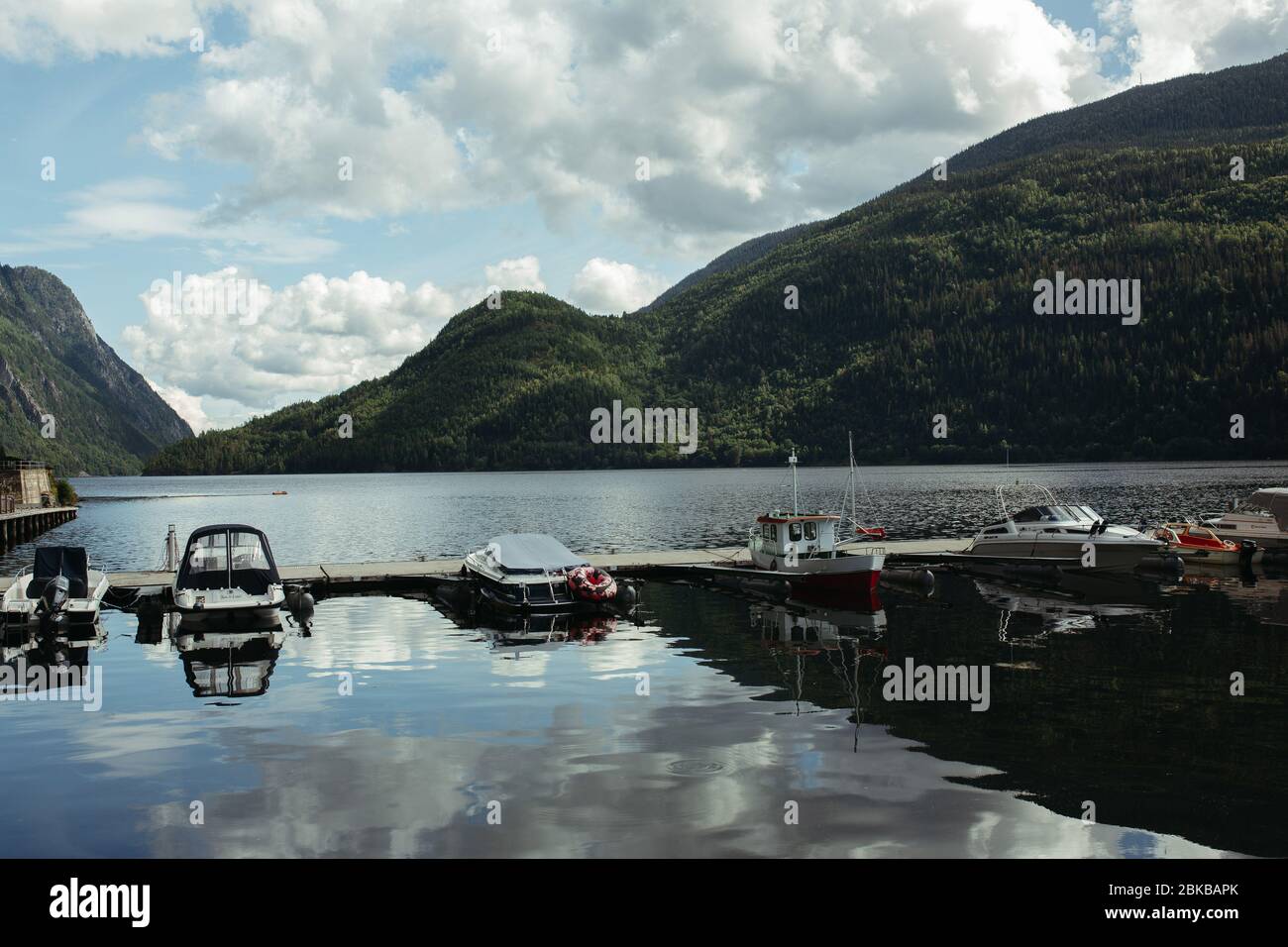 Boote in Pristan auf einem Bergfluss in norwegen gegen einen blauen Himmel mit Wolken bei sonnigem Wetter Stockfoto