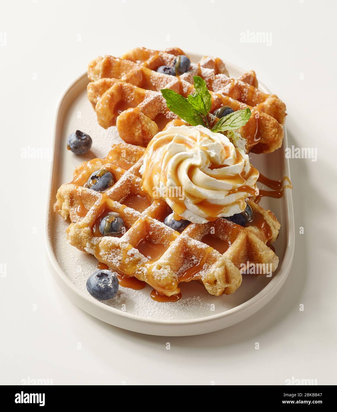 Teller mit belgischen Waffeln Dessert mit Schlagsahne, Karamellsauce und frischen Beeren dekoriert Stockfoto