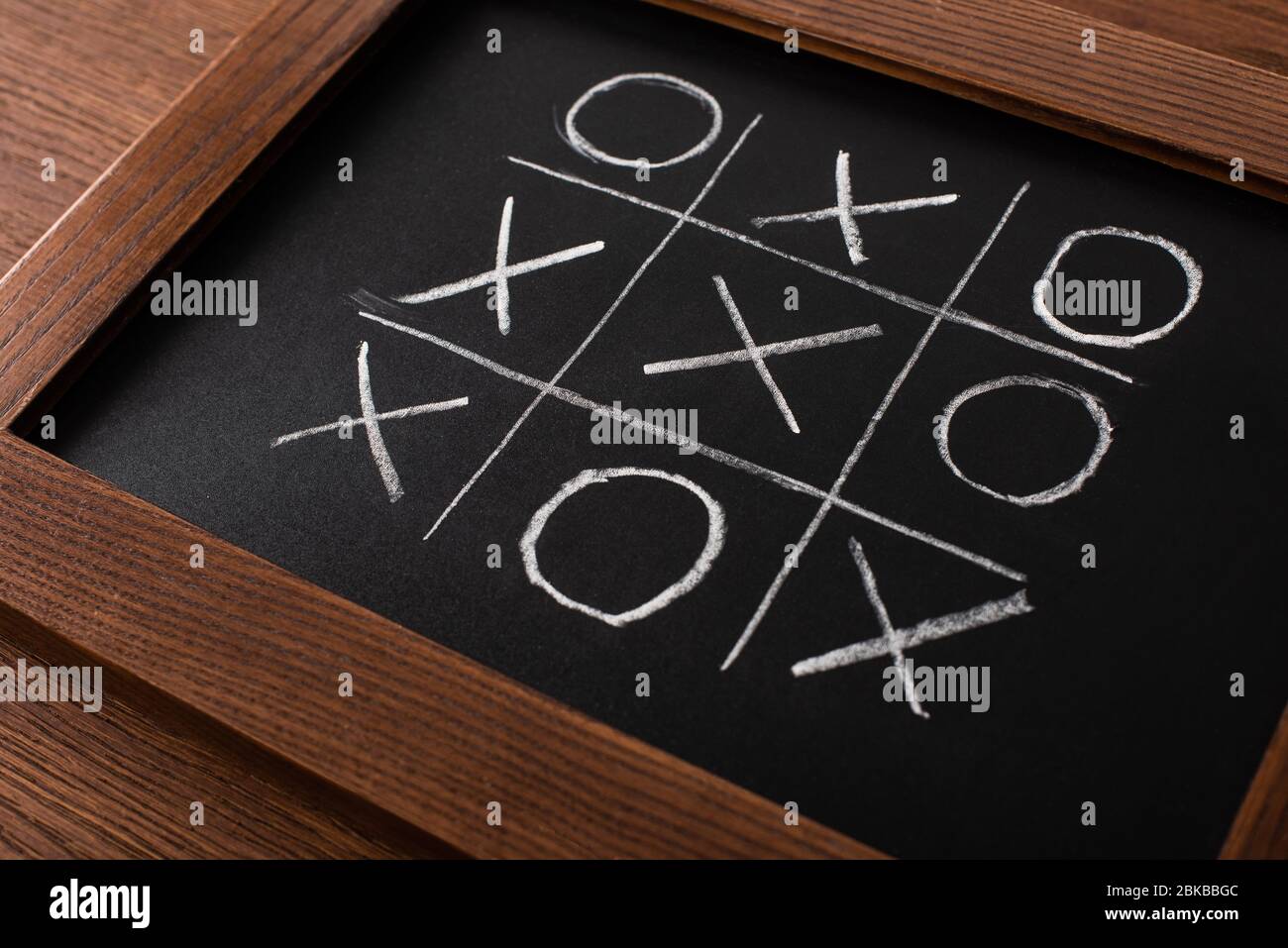 tic tac Zehen Spiel auf Tafel mit Kreide Gitter, Naughts und Kreuze auf Holzfläche Stockfoto