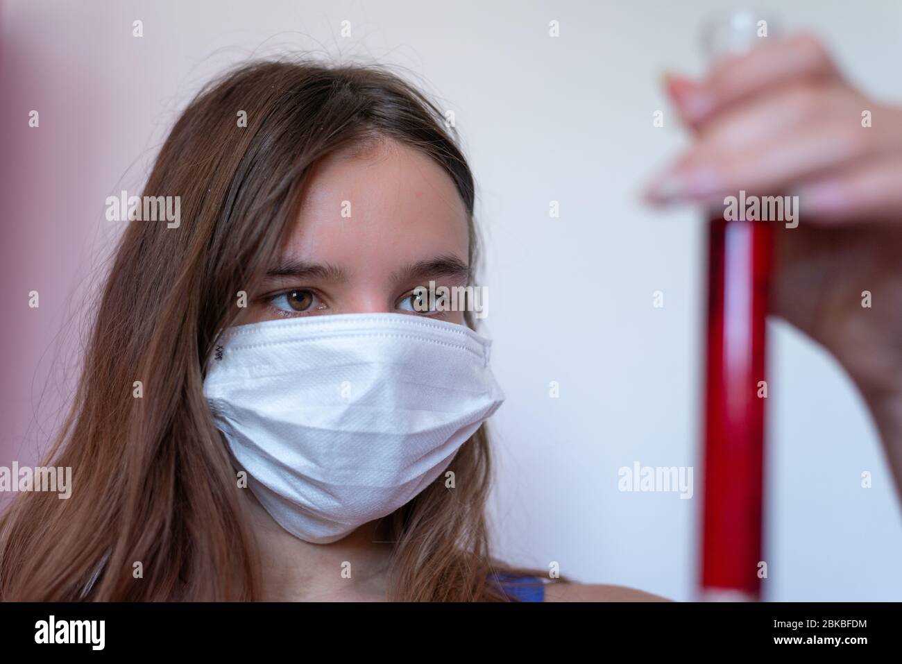 Junge Wissenschaftlerin Untersuchung Fläschchen Blut , Frau mit medizinischer Gesichtsmaske Blick auf Probe Blutprobe Tube, Kampf gegen Covid 19 Stockfoto