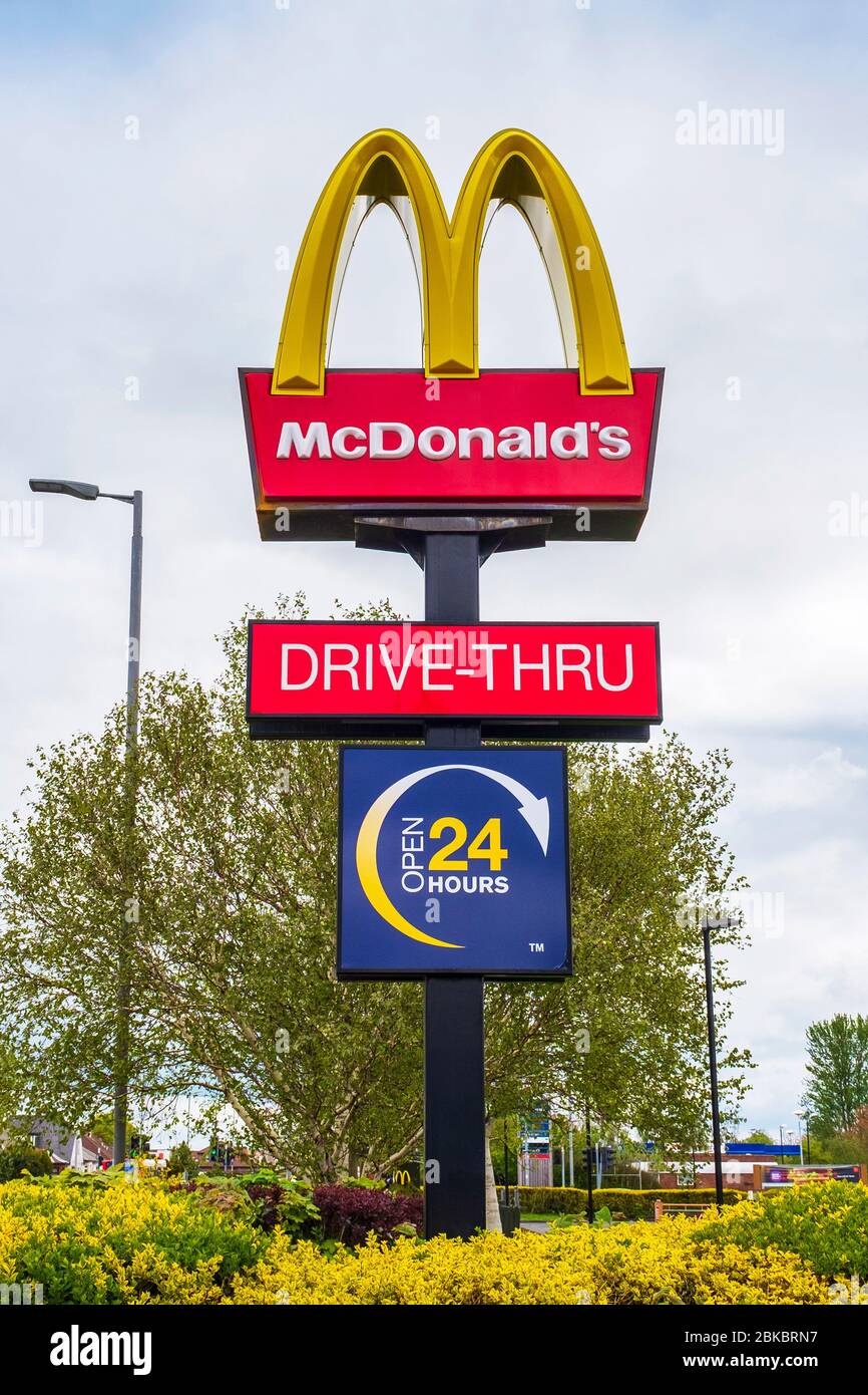 Firmenlogo und Marke von McDonald's Drive-Thru Fast Food Restaurant und dem 24-Stunden-Schild „Open“, Ayr, Großbritannien Stockfoto