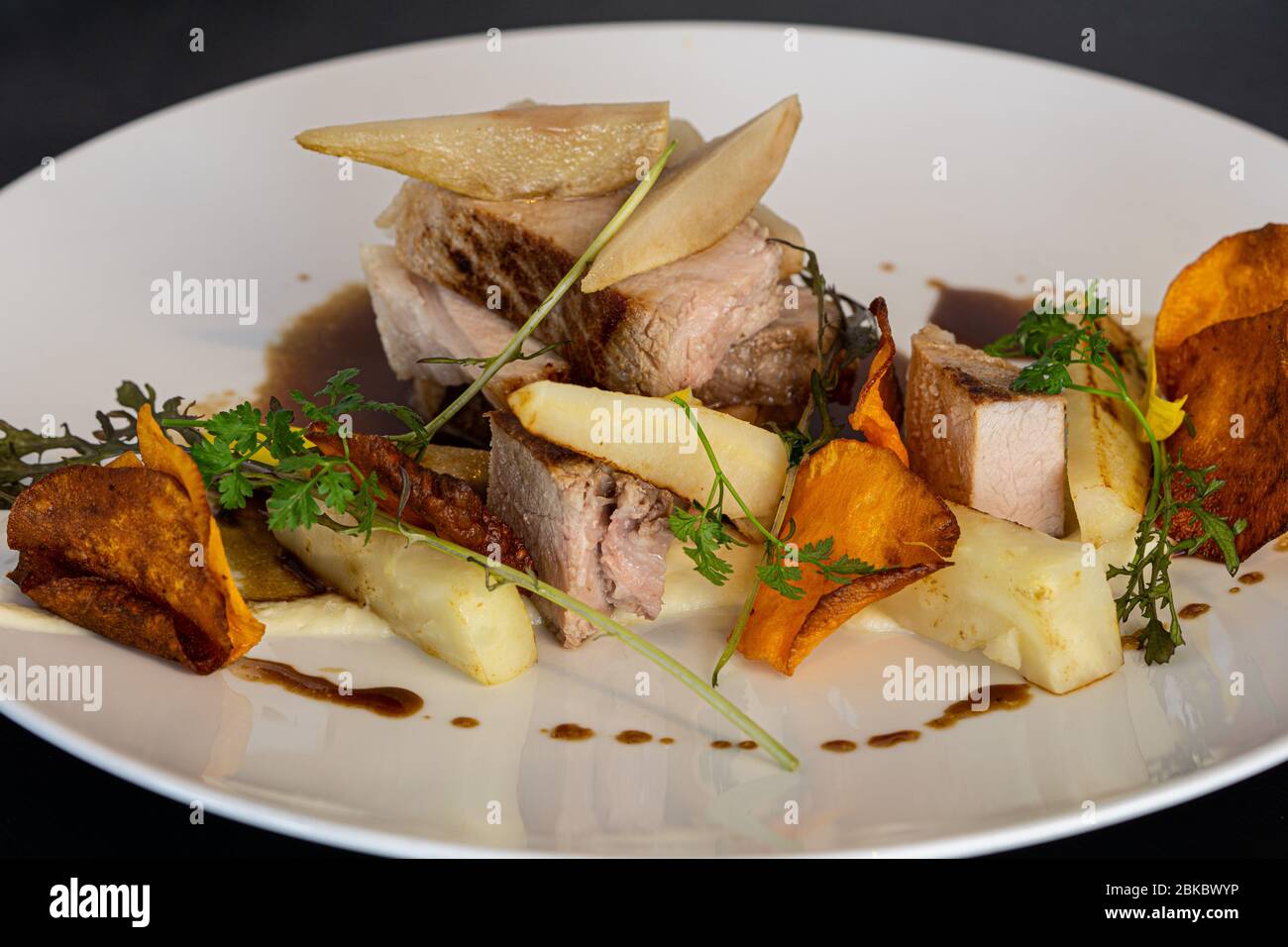 Gebratenes Schweinefleisch Scheiben mit gebratenen Kartoffelchips, gebackene Birne. Stockfoto