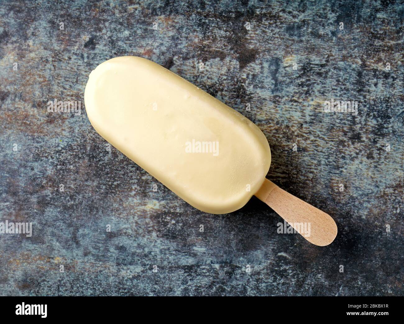 Eis mit weißer Schokolade auf bunt bedrucktem Teller Hintergrund bedeckt, Draufsicht Stockfoto